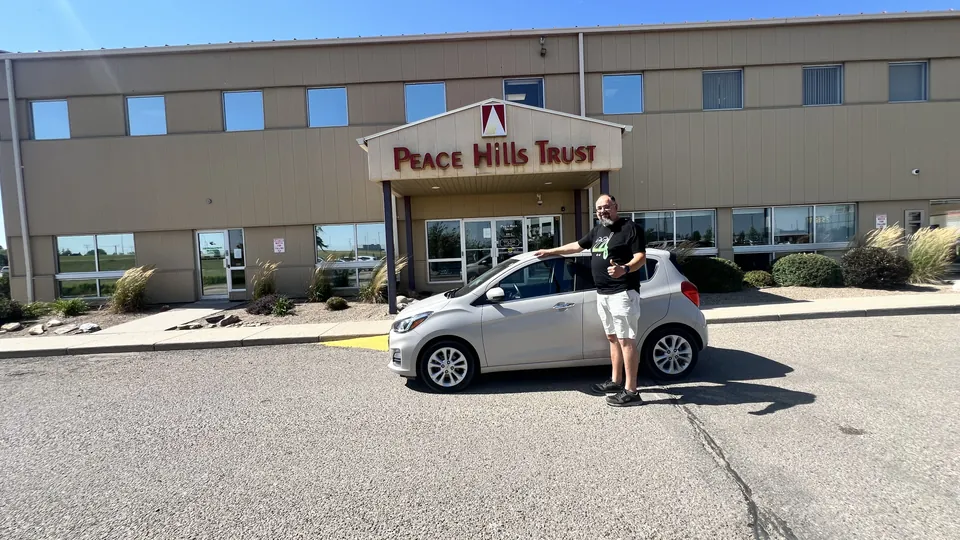 A person beside a silver car outside the dealership entrance