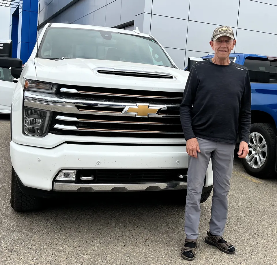 A person beside a white pickup outside the dealership