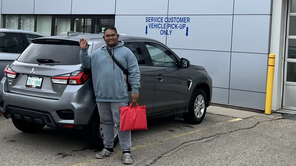 A person beside a grey SUV outside the service entrance