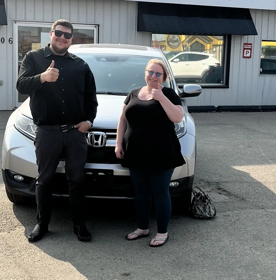 Two people beside a white SUV outside the dealership