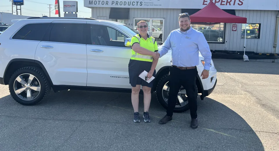 Two people beside a white SUV in the vehicle lot