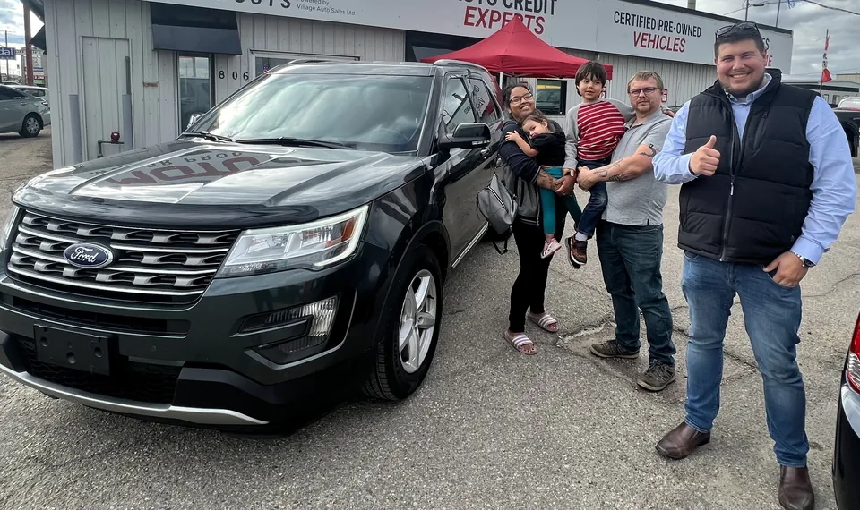 A group beside a black SUV outside the dealership