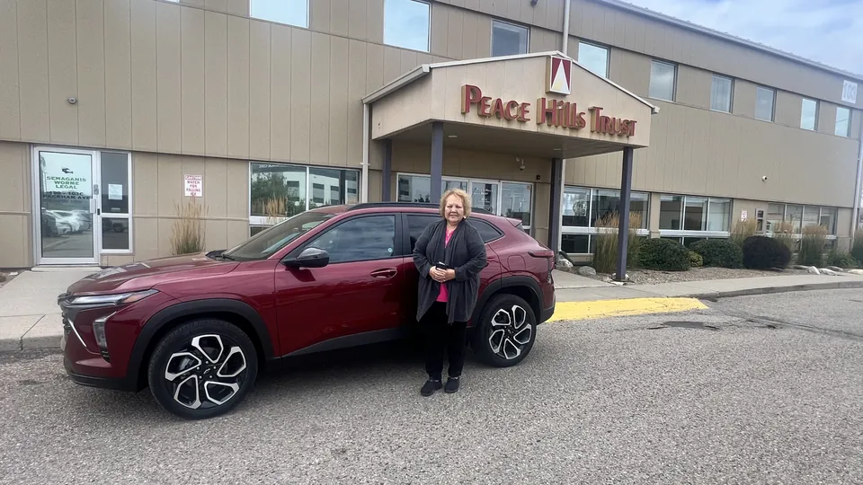 A person beside a red SUV at the dealership entrance