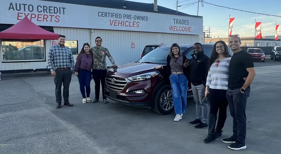 A group beside a red SUV outside the dealership