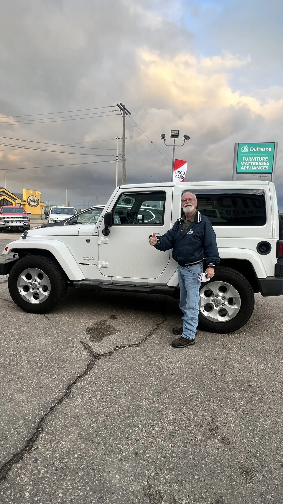 A person beside a white SUV at sunset