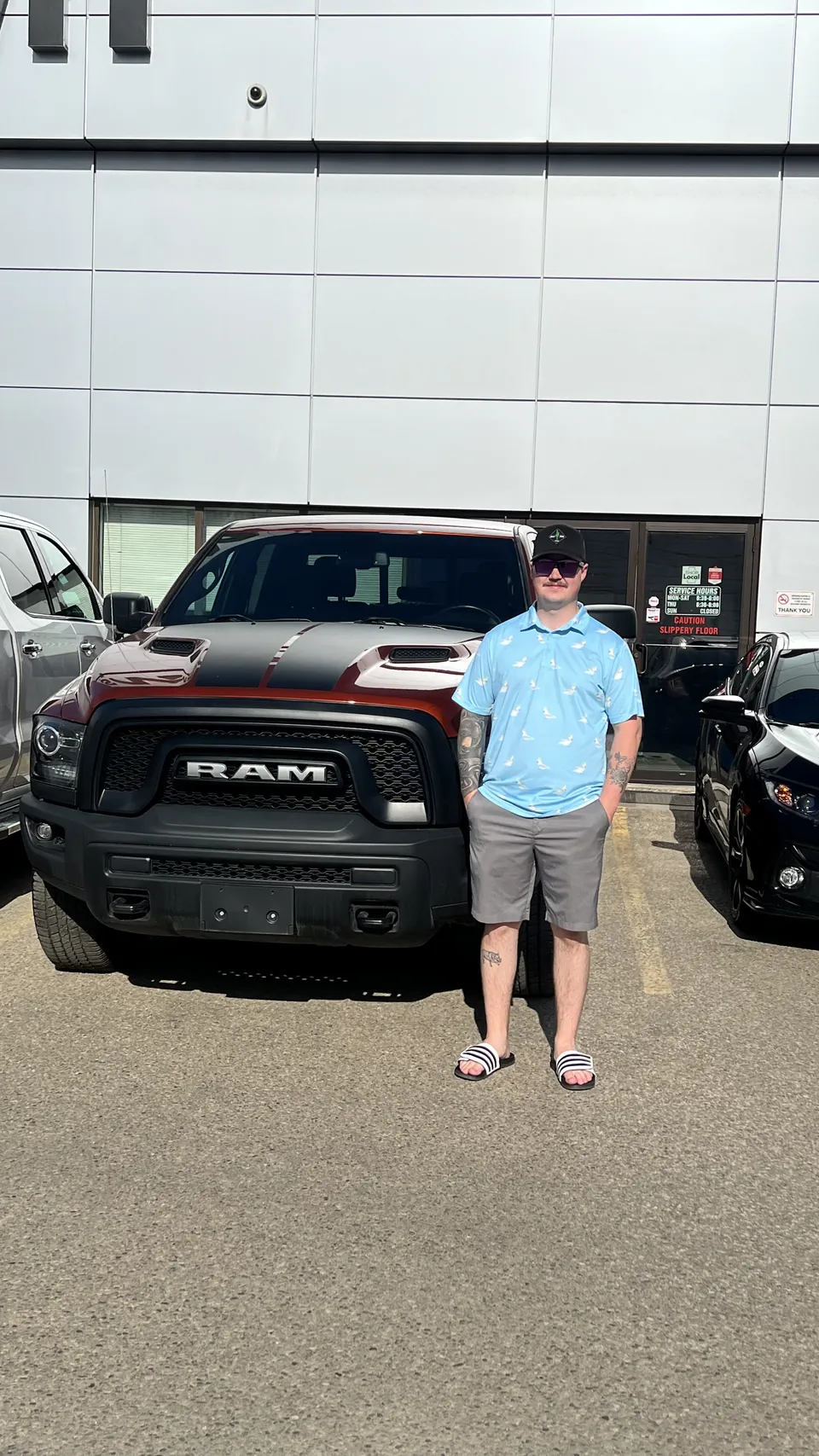 A person beside a black pickup outside the dealership