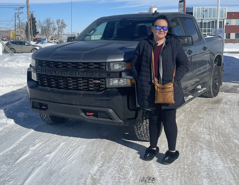 A person beside a dark pickup on a snowy day