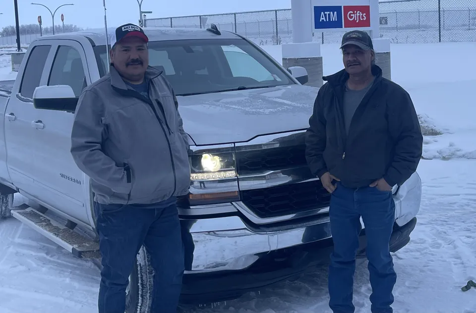 Two people beside a pickup on a snowy day