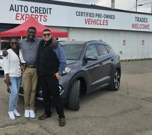 Two people beside a grey SUV outside the dealership
